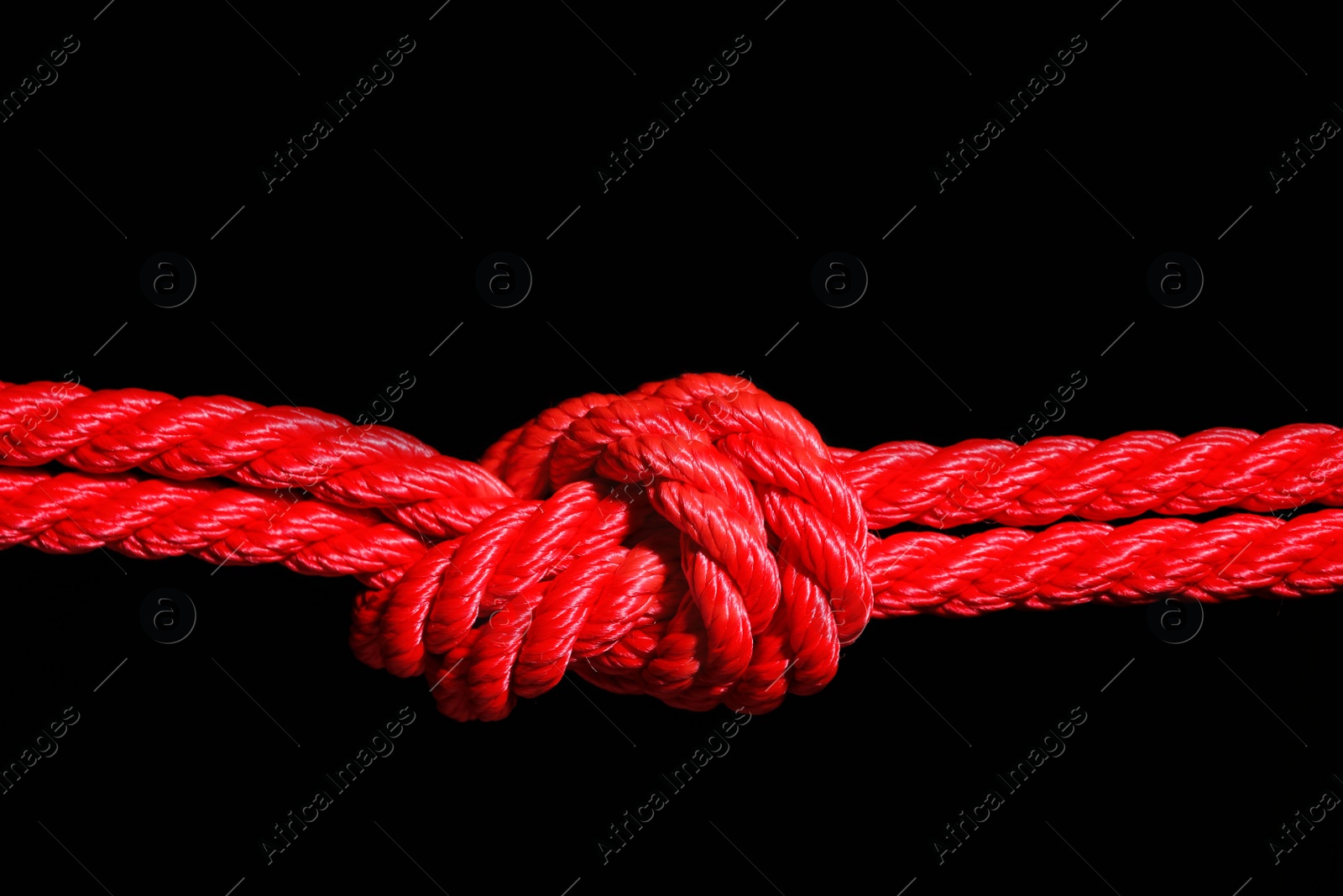 Photo of Red rope with knot on black background