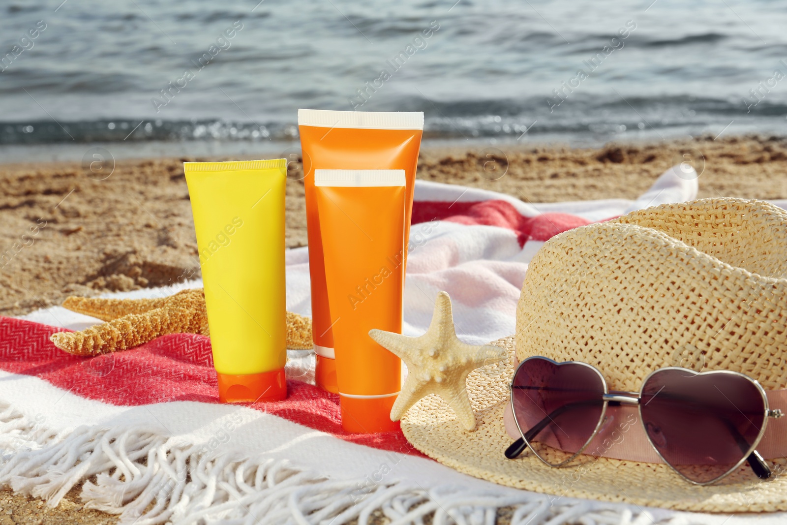 Photo of Sun protection products and beach accessories on blanket near sea