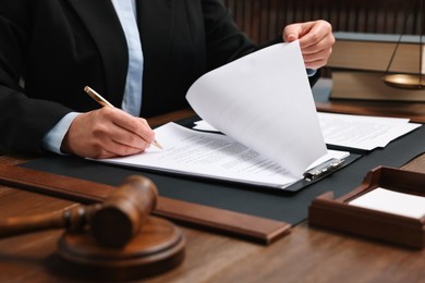 Lawyer working with documents at wooden table indoors, closeup