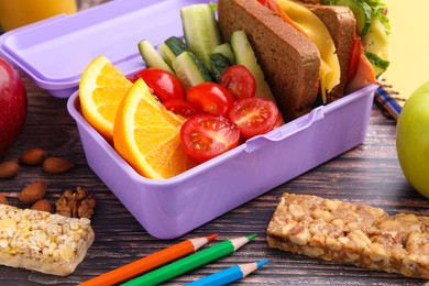 Photo of Lunch box with healthy food for schoolchild and different stationery on wooden table, closeup