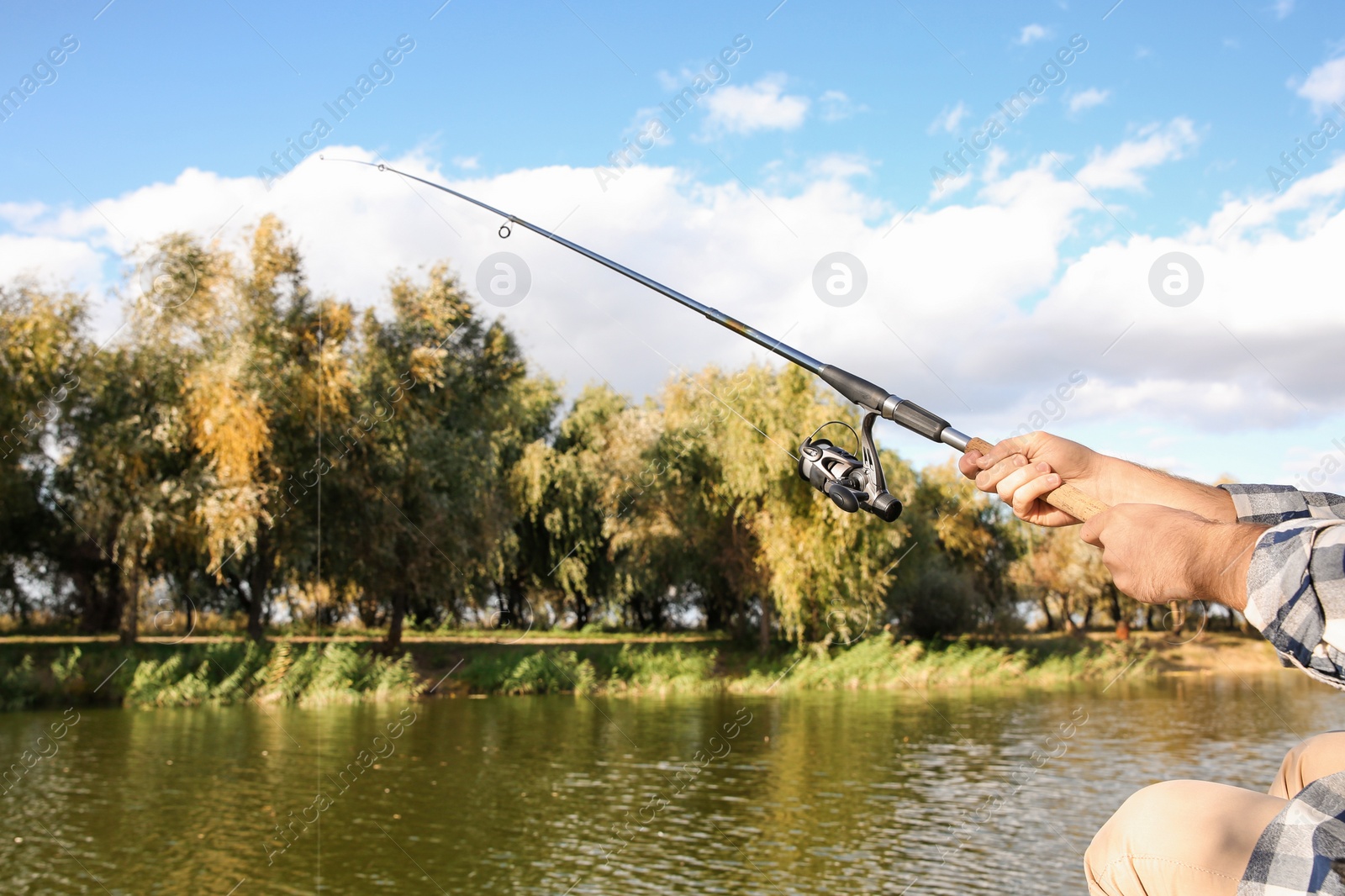 Photo of Man with rod fishing at riverside, focus on hands. Recreational activity