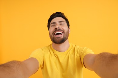 Photo of Smiling man taking selfie on yellow background