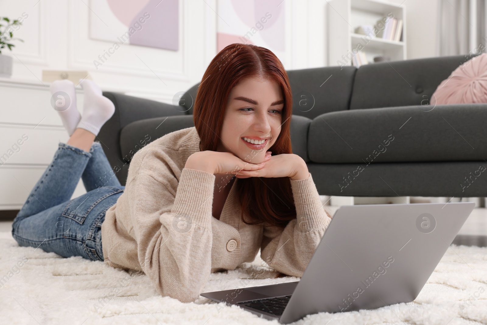 Photo of Happy woman with laptop on rug in living room