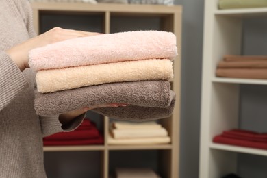 Photo of Woman holding stack of towels in bed linen shop, closeup. Space for text