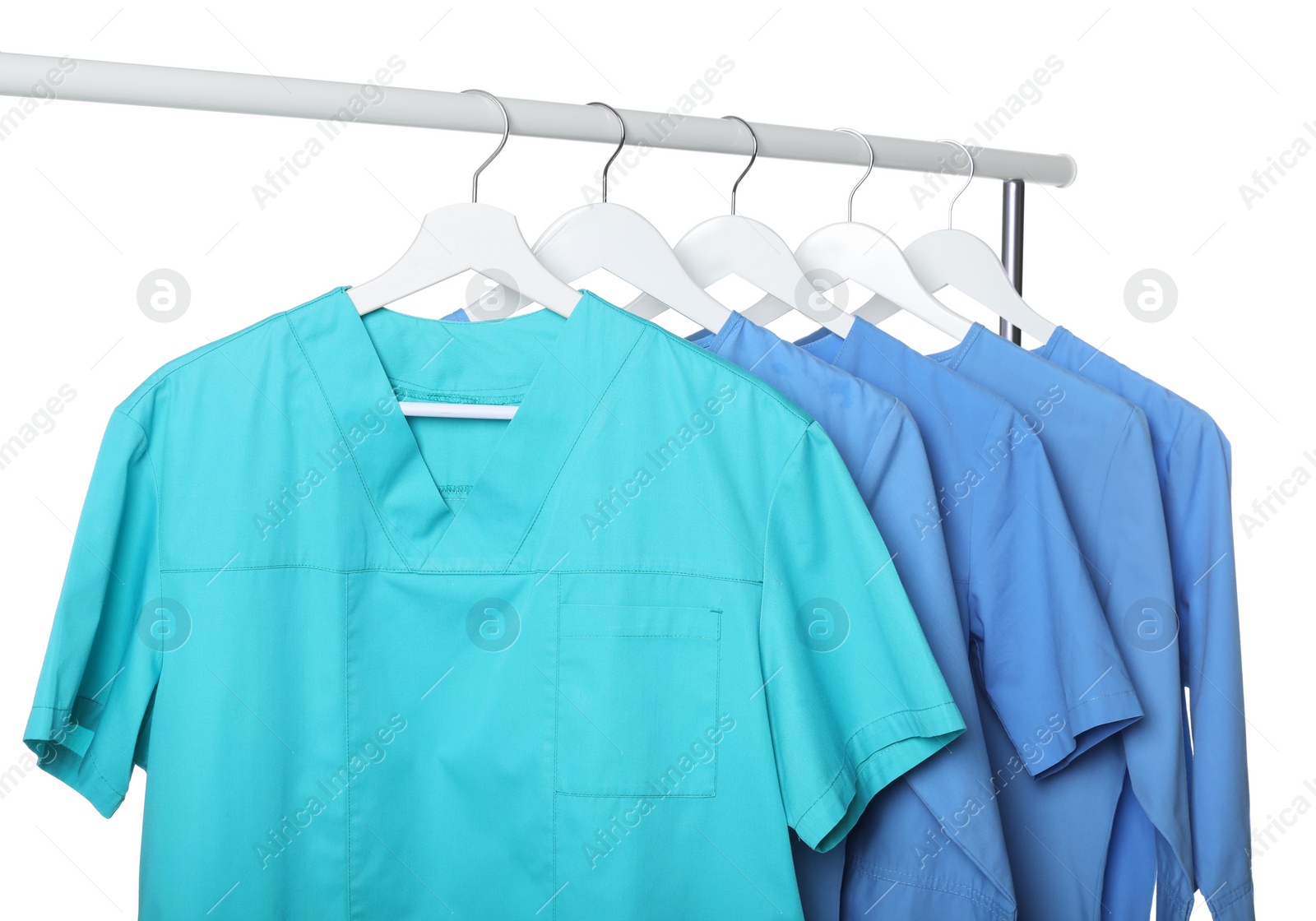 Photo of Turquoise and light blue medical uniforms on rack against white background