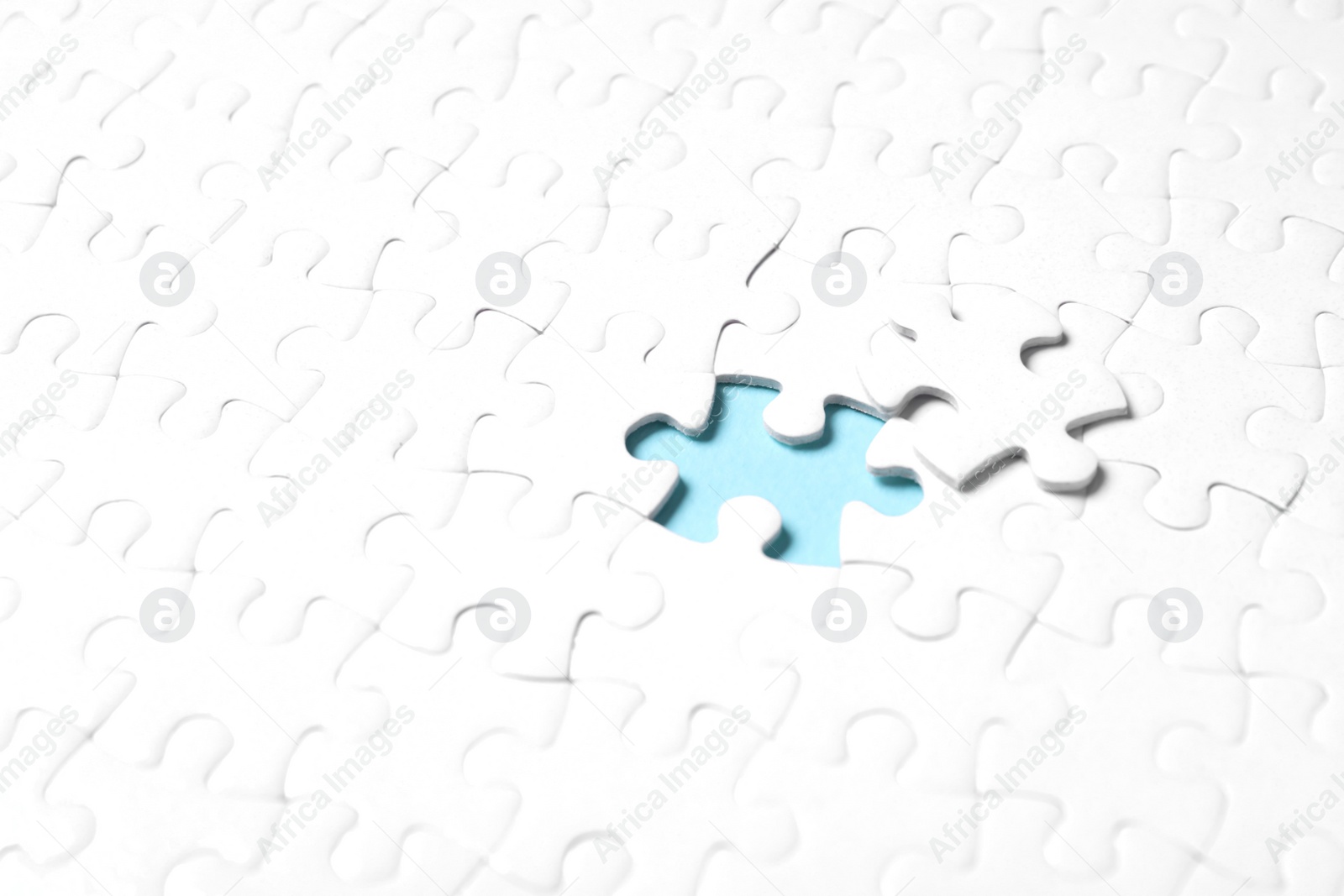 Photo of Blank white puzzle with separated piece on light blue background