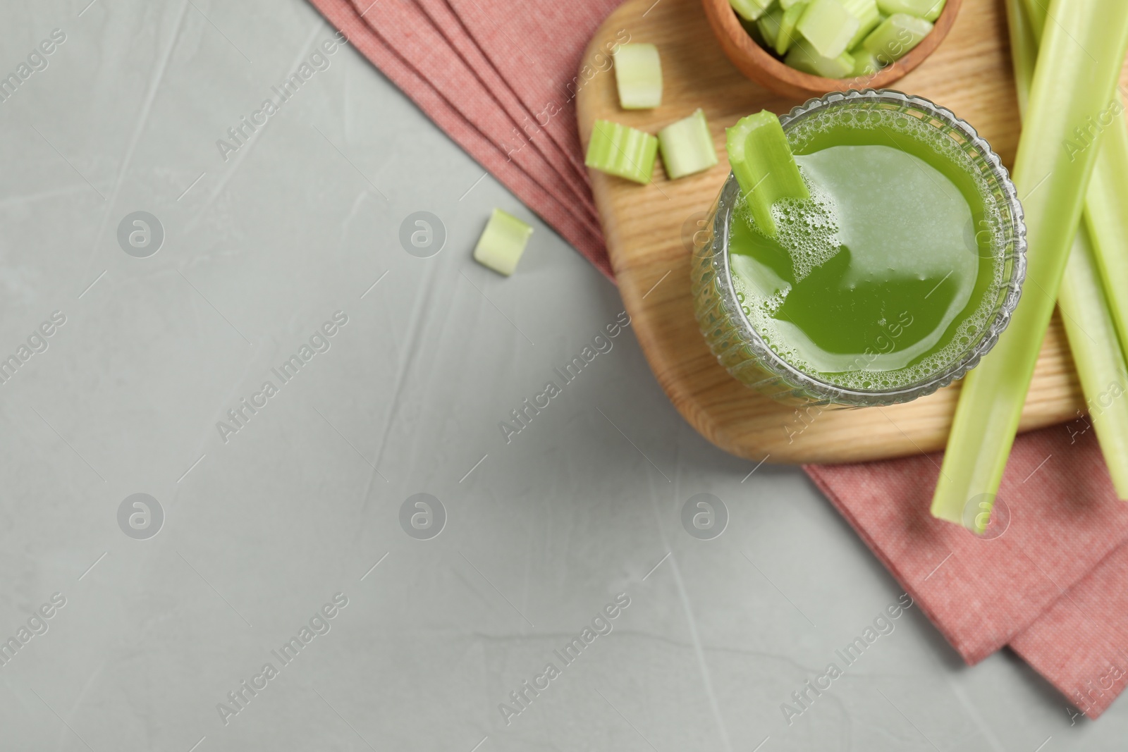 Photo of Glass of delicious celery juice and vegetables on grey table, flat lay. Space for text