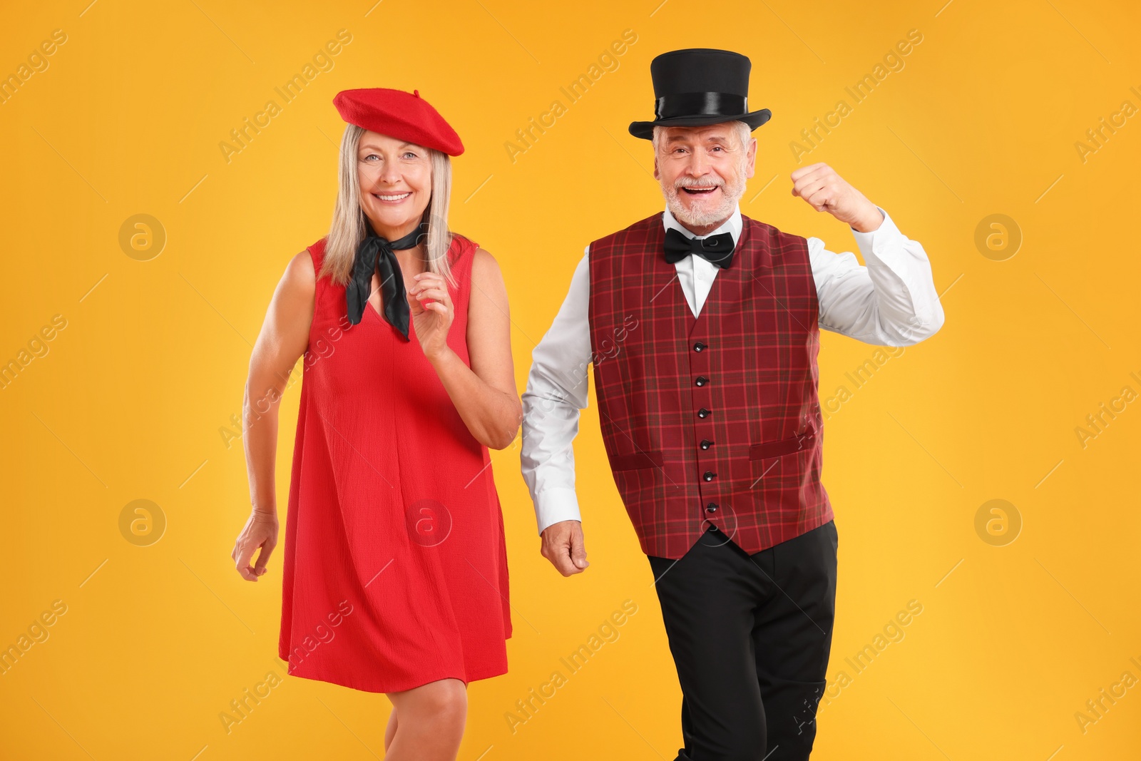 Photo of Senior couple dancing together on orange background