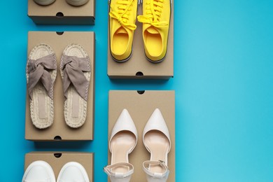 Photo of Stylish women's shoes and cardboard boxes on light blue background, flat lay. space for text