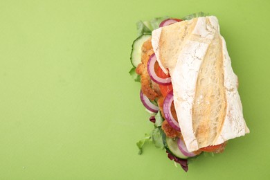 Photo of Delicious sandwich with schnitzel on green background, top view. Space for text