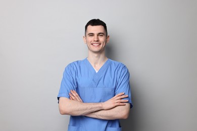 Photo of Portrait of smiling medical assistant with crossed arms on grey background