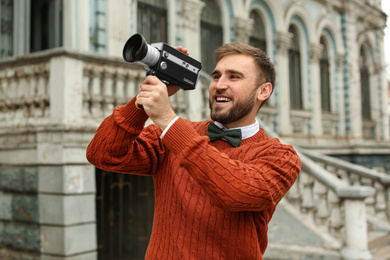 Photo of Young man with vintage video camera outdoors