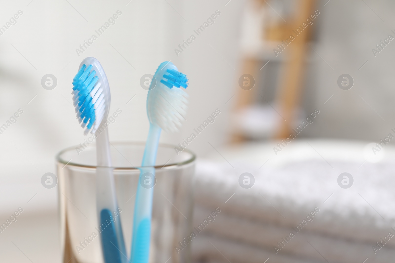 Photo of Plastic toothbrushes in glass holder on blurred background, closeup. Space for text