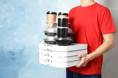 Photo of Courier with stack of orders on color background, space for text. Food delivery service