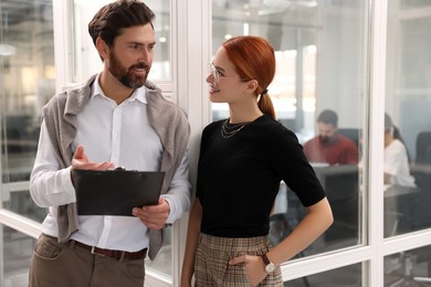 Photo of Beautiful woman and man with clipboard in office. Team work