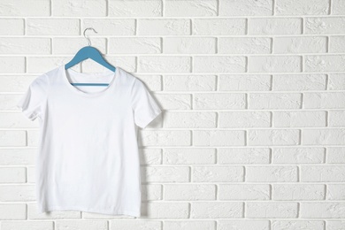 Hanger with white t-shirt against brick wall. Mockup for design