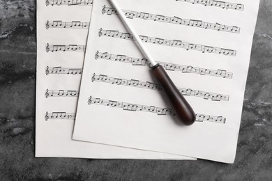 Conductor's baton and sheet music on grey table, flat lay