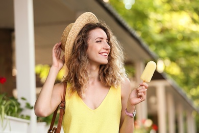 Happy young woman with delicious ice cream outdoors