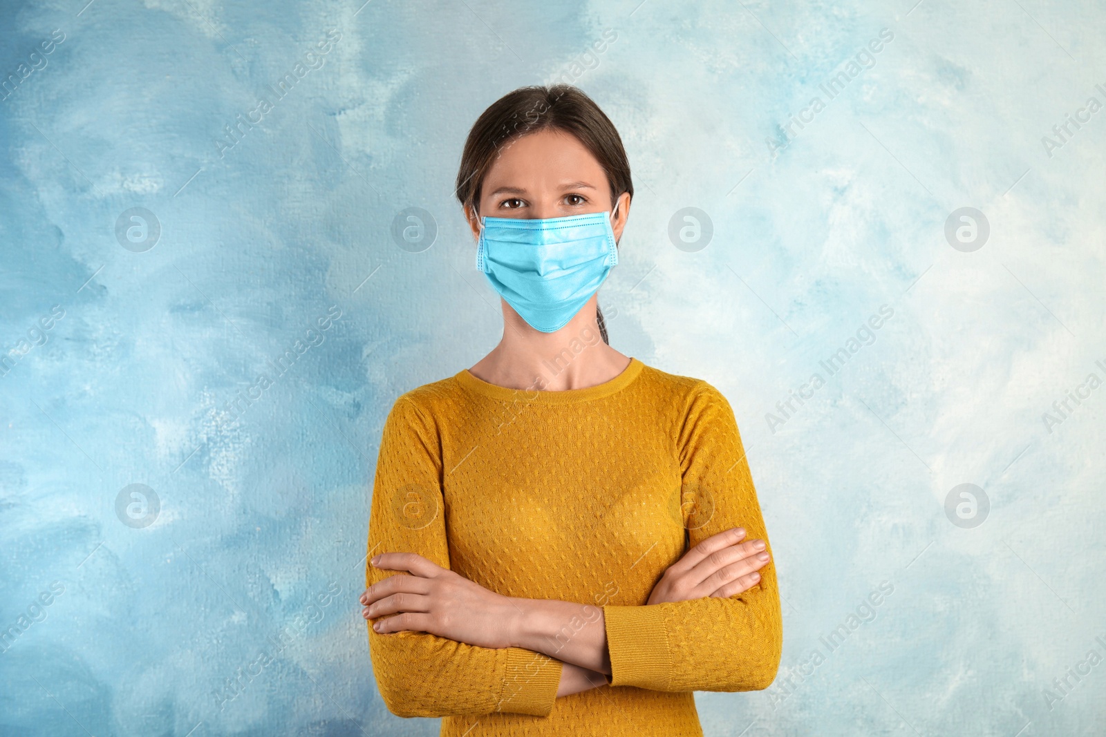 Photo of Woman with disposable mask on face against light blue background