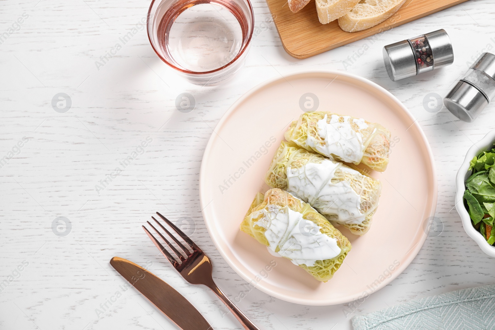 Photo of Delicious cabbage rolls served on white wooden table, flat lay