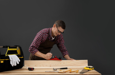 Photo of Handsome carpenter working with timber at table on black background
