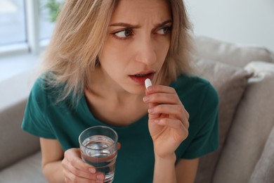 Photo of Upset young woman taking abortion pill at home, closeup