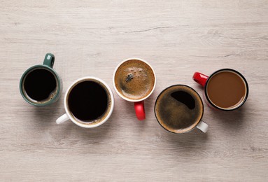 Many different cups of coffee on white wooden table, flat lay