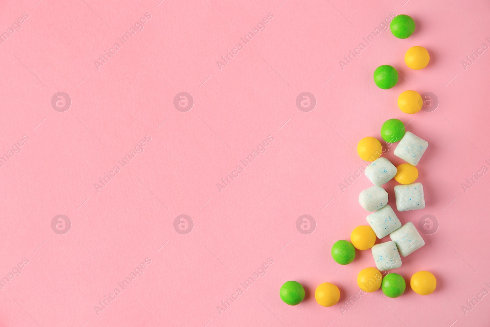 Photo of Different tasty chewing gums on pink background, flat lay. Space for text