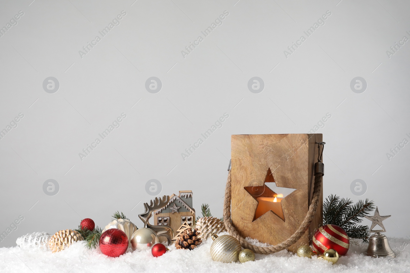 Photo of Composition with wooden Christmas lantern on snow against light grey background, space for text