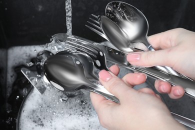Woman holding clean silver kitchenware near sink, closeup