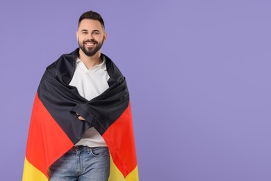 Photo of Young man with flag of Germany on purple background, space for text