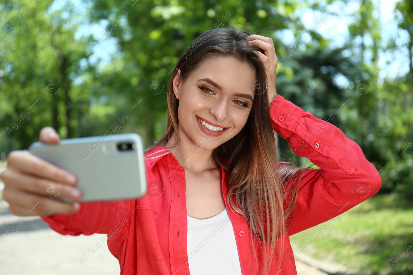 Photo of Happy young woman taking selfie in park