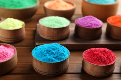 Photo of Colorful powder dyes on wooden background, closeup. Holi festival