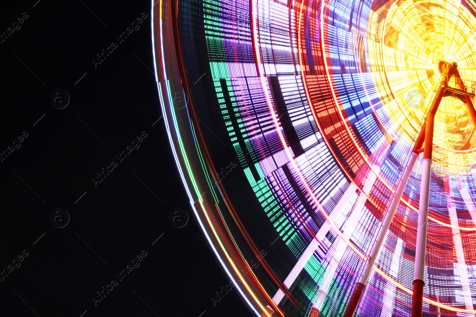 Photo of Beautiful glowing Ferris wheel against dark sky, low angle view. Space for text