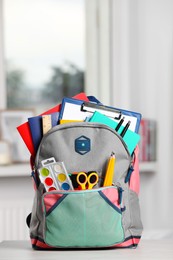 Photo of Backpack with different school stationery on white table indoors