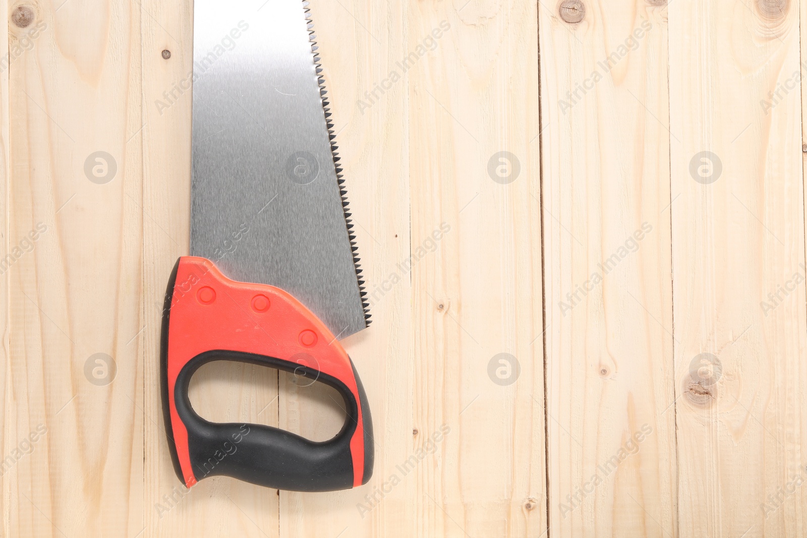 Photo of Saw with colorful handle on wooden background, top view. Space for text