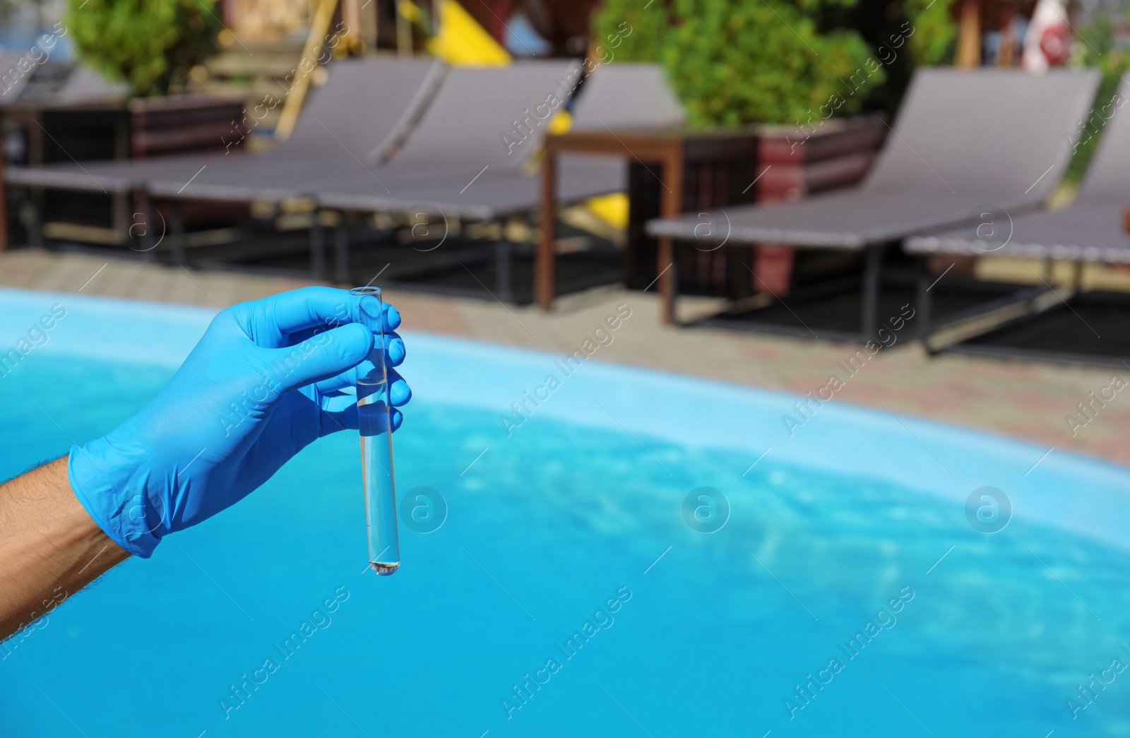 Photo of Man holding test tube with water against swimming pool on sunny day. Space for text