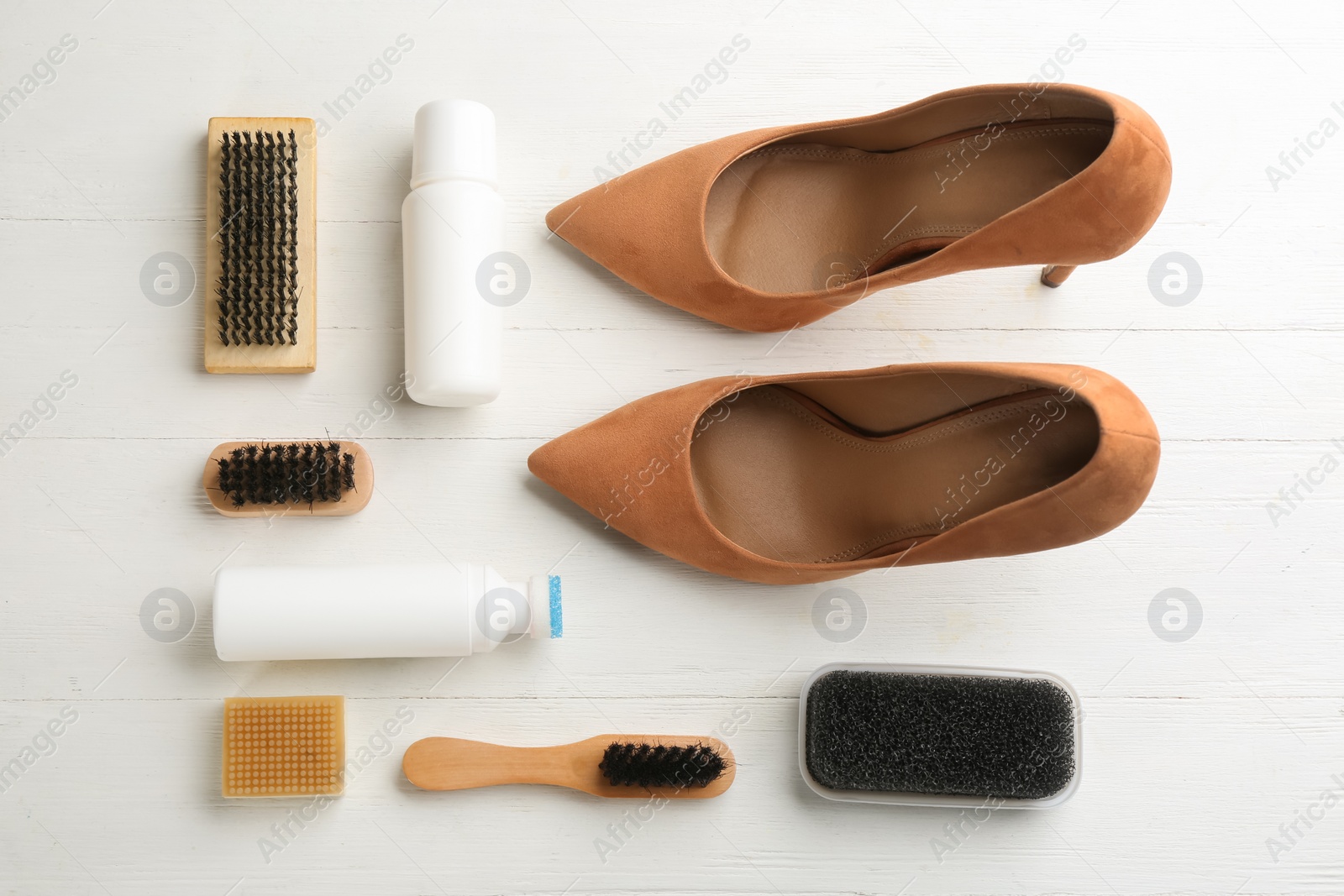 Photo of Stylish footwear with shoe care accessories on white wooden table, flat lay