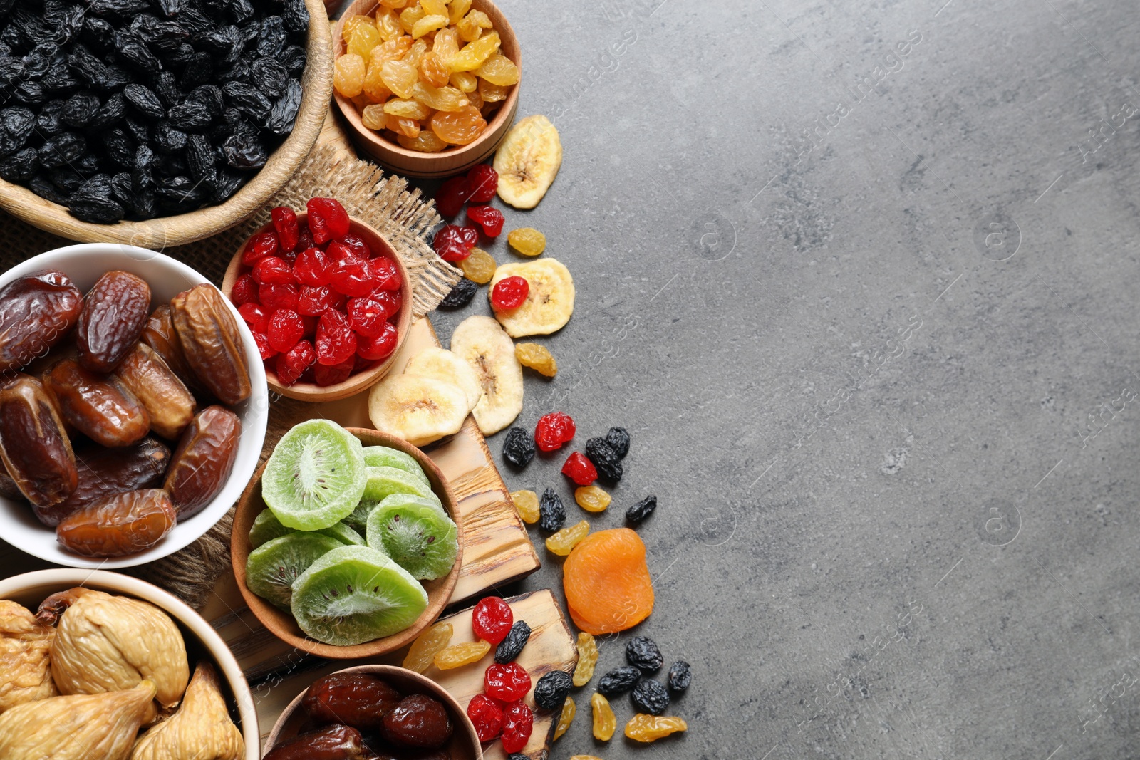 Photo of Bowls of different dried fruits on grey background, top view with space for text. Healthy food