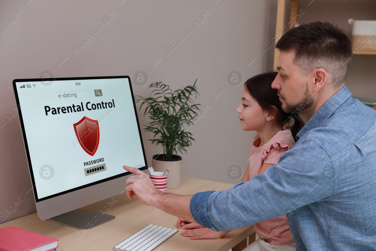 Photo of Dad installing parental control on computer at table indoors. Child safety