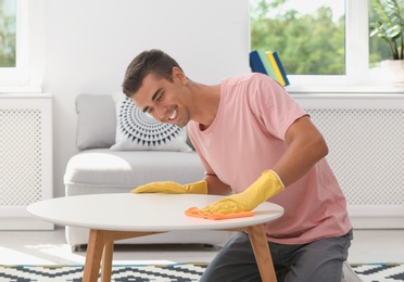 Man cleaning table with rag in living room