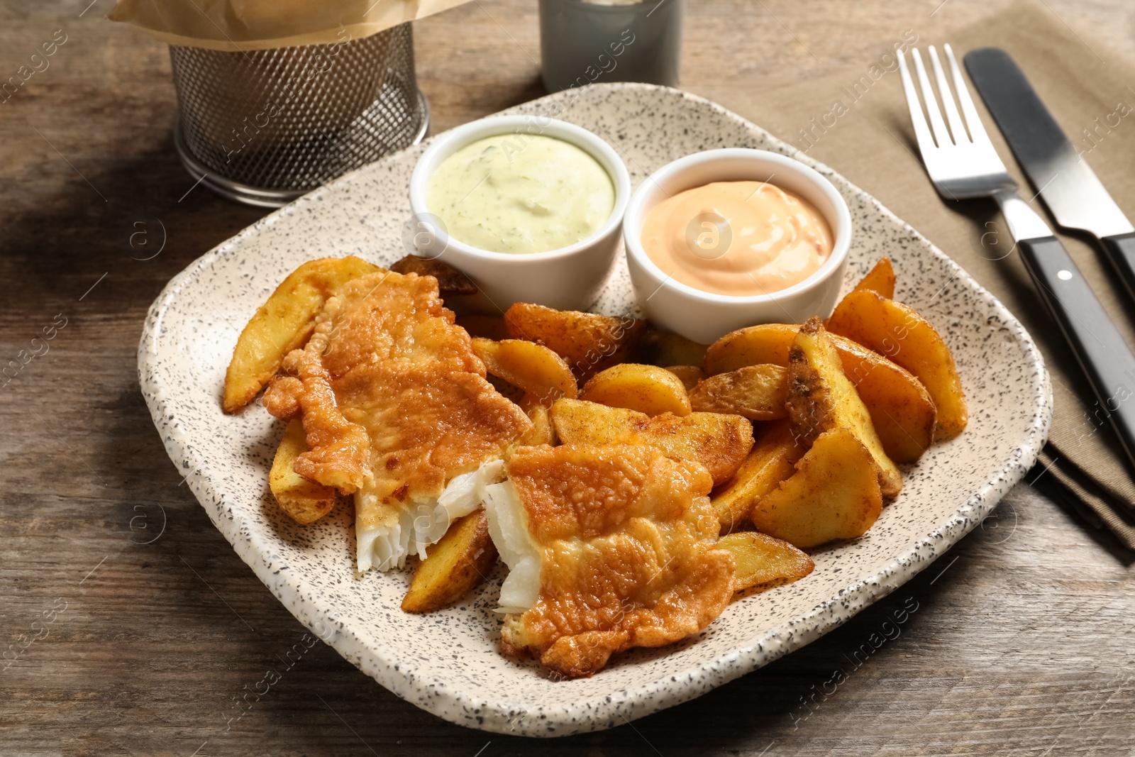 Photo of Plate with British traditional fish and potato chips on wooden table