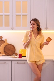 Photo of Beautiful young woman having breakfast in kitchen. Weekend morning