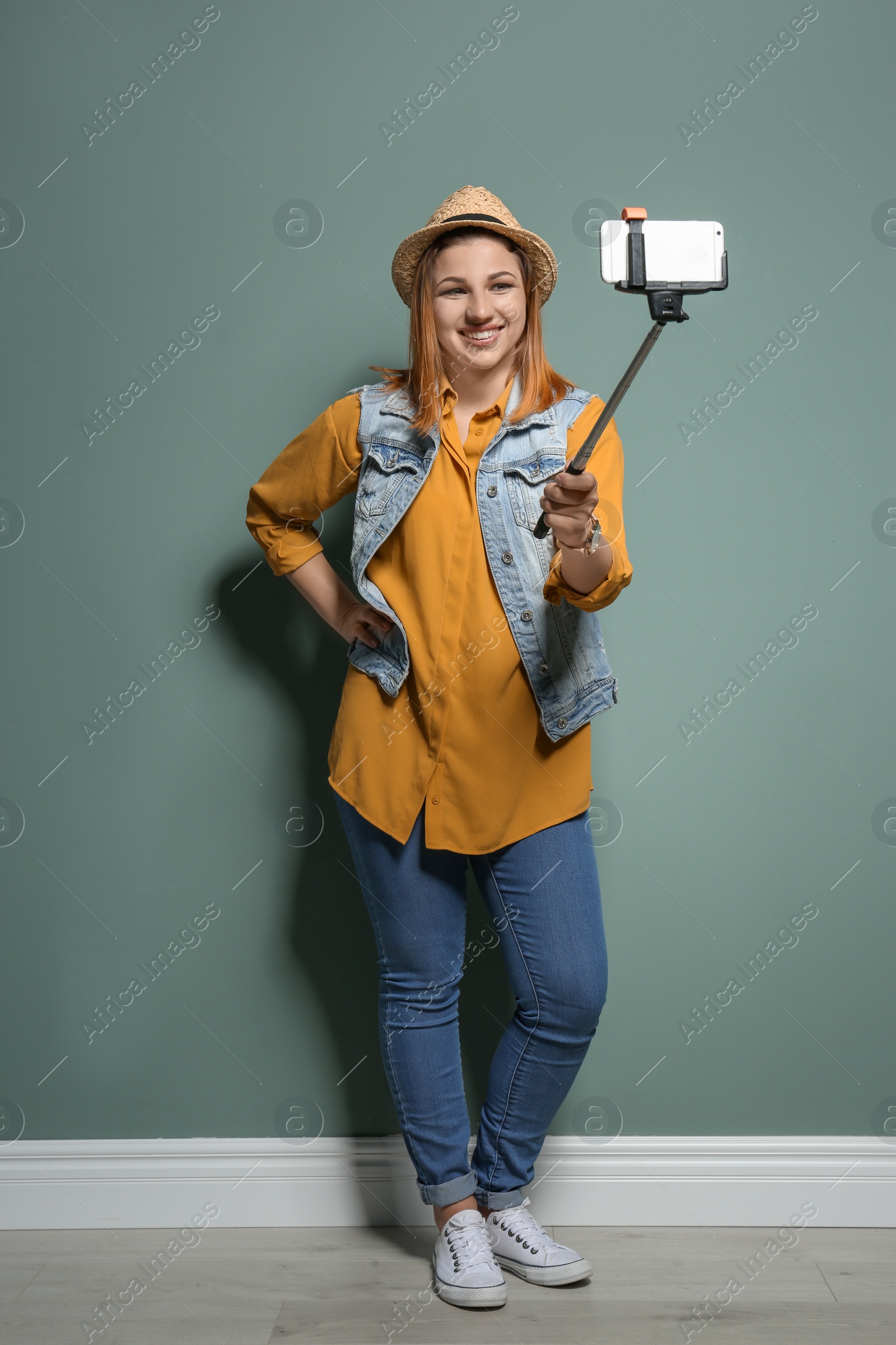 Photo of Attractive young woman taking selfie near color wall