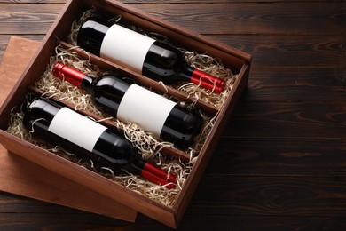 Photo of Box with wine bottles on wooden table, above view. Space for text