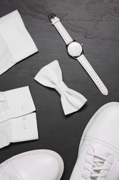 Photo of Stylish white bow tie, shoes, wristwatch and shirt on grey background, flat lay