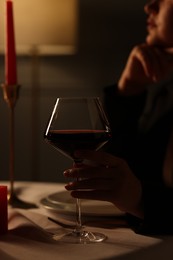 Beautiful young woman with glass of wine at table in restaurant, closeup