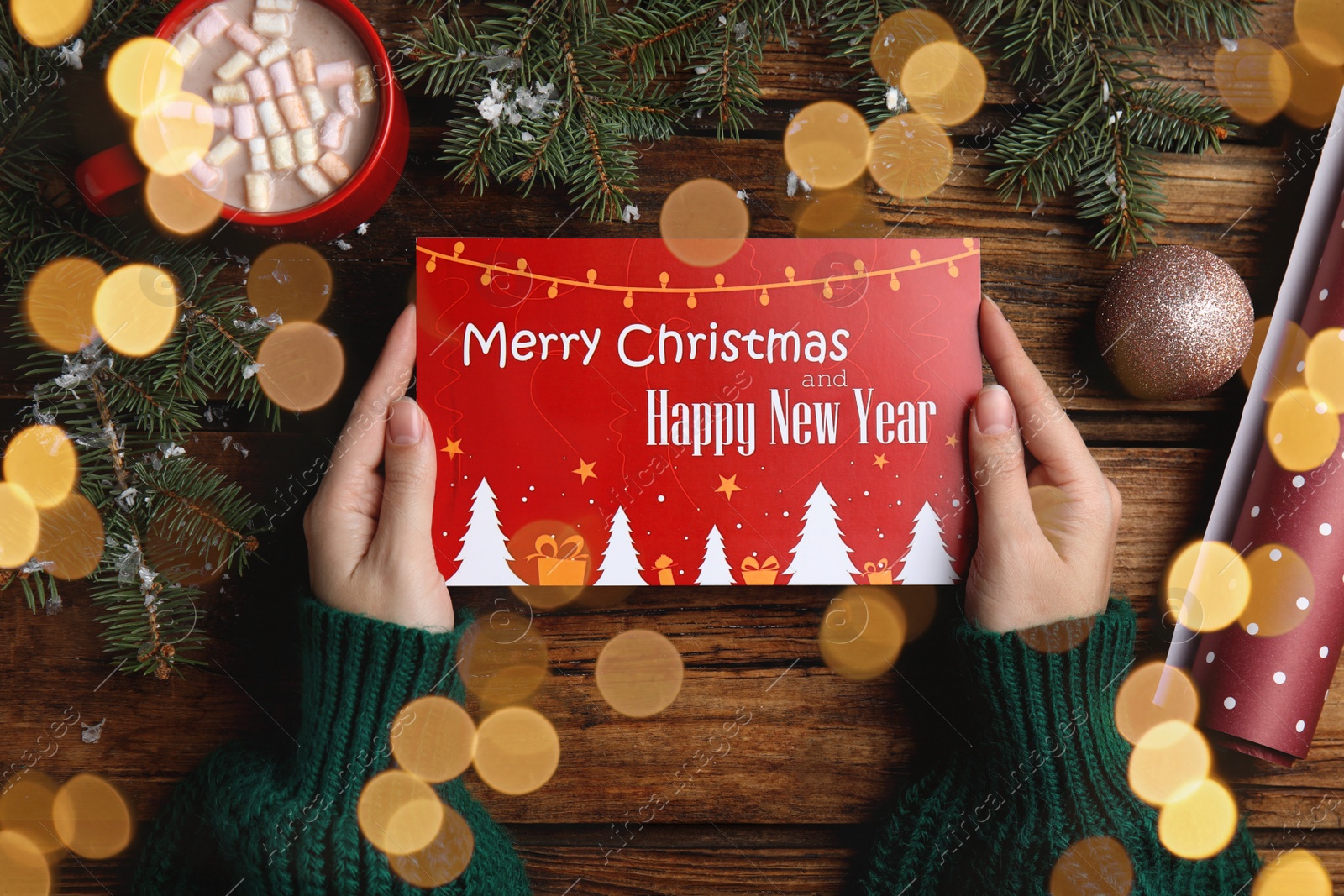 Photo of Woman holding greeting card at wooden table, top view. Christmas celebration