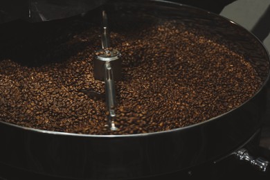 Photo of Modern coffee roaster machine with beans indoors, closeup