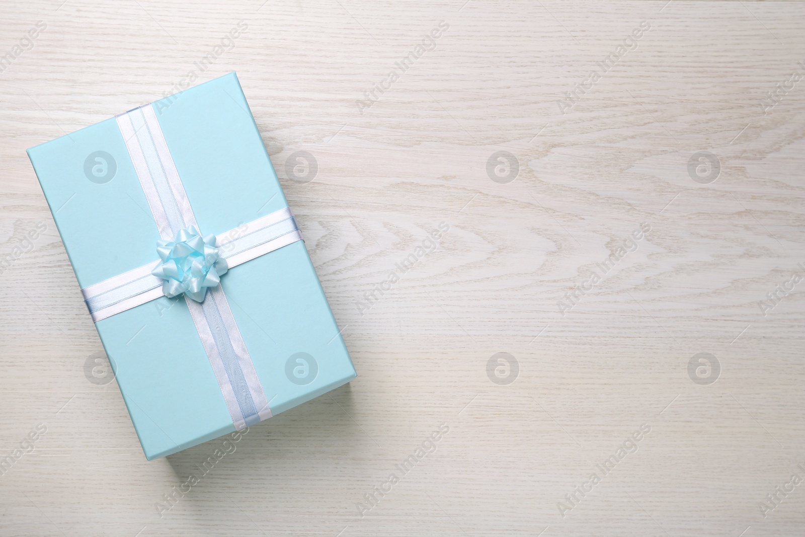 Photo of Light blue gift box on white wooden table, top view. Space for text